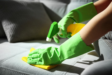 Cleaning concept. Young woman cleans sofa in the room, close up