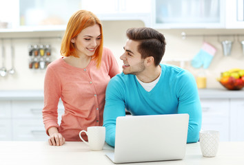 Young beautiful couple with cup of tea using laptop
