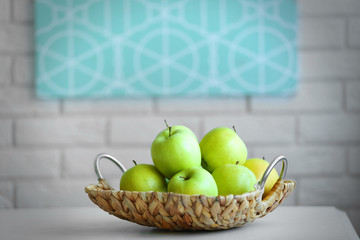 Ripe green apples in a wicker basket on a kitchen table