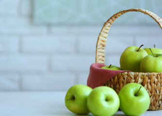 Ripe green apples in basket on a kitchen table