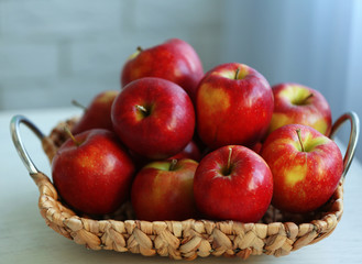 Ripe red apples in wicker basket on a kitchen table