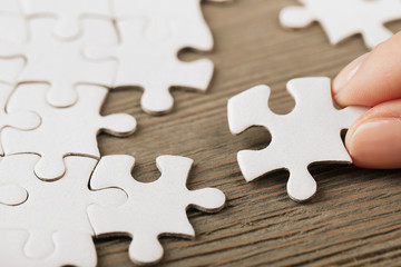 Woman playing with jigsaw puzzle on wooden table