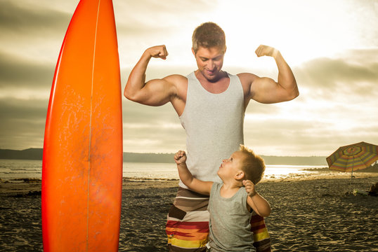 Young man and son flexing muscles on beach