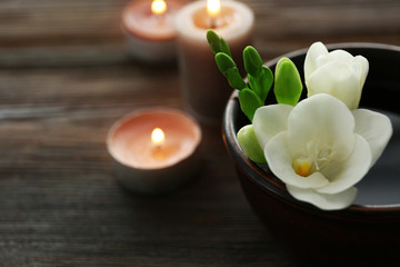 Obraz na płótnie Canvas Beautiful flower in the bowl with water and candles on wooden background
