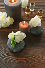 Spa composition with candle, pebbles and aroma oil on wooden background