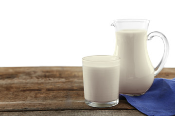 Jug and cup of milk on wooden table