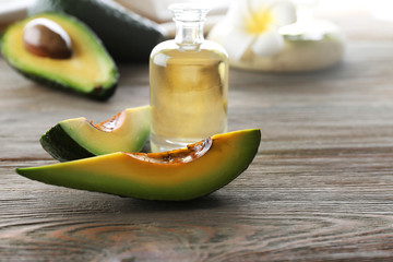 Fresh avocados with an oil on a wooden table, close up