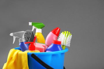 Bucket of cleaning supplies on a grey background