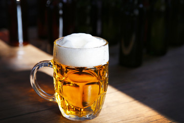 Glass mug of light beer on wooden table