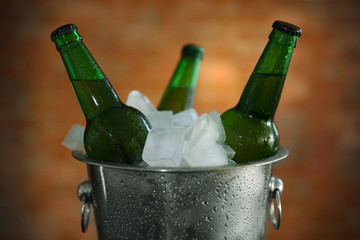 Green glass bottles of beer in ice-pail, close up