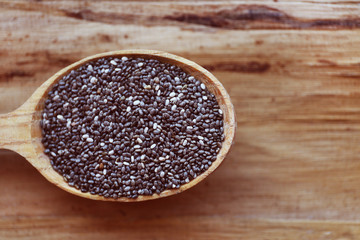 Spoon of chia seeds on wooden background