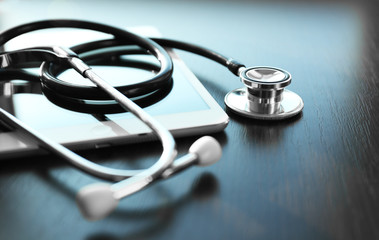 Stethoscope and tablet on dark wooden background