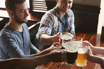 Group of happy friends drinking beer in pub