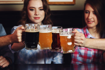 Beautiful girls and their friends drinking beer in pub