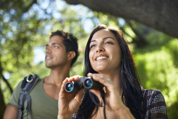 Couple with binoculars birdwatching in forest