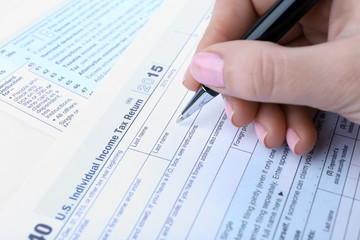 Obraz premium Female hand filling in the Income Tax Form, close up