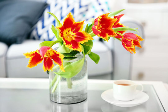 A bouquet of red tulips in a glass on white table.
