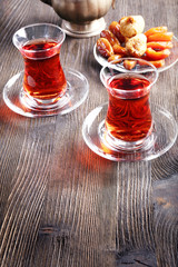 Black brewed tea in glass cups with eastern sweets on wooden table