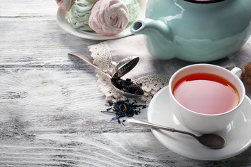 Black tea with ceramic utensils and sweets on white wooden table