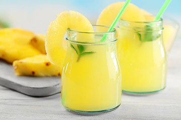 Obraz na płótnie Canvas Pineapple cocktail in glass jars on wooden table closeup