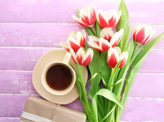 Bouquet of variegated tulips with cup of coffee and gift box on wooden background