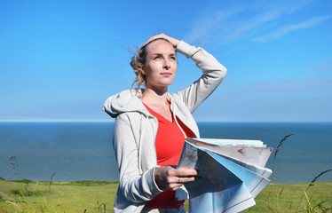 Young woman holding map by sea