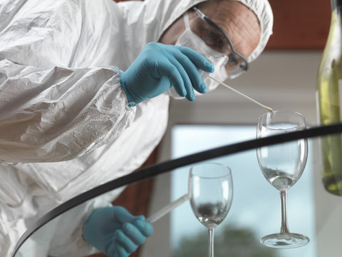 Forensic scientist using a DNA swab to take evidence from a glass at a scene of crime