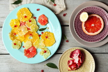 Cutting citruses and pomegranate on plate