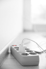 Mobile phone charging into power cord on wooden floor indoors