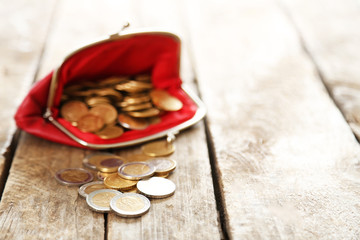 Open red purse and euro coins on wooden table