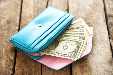 Open blue purse with dollar banknotes on wooden table