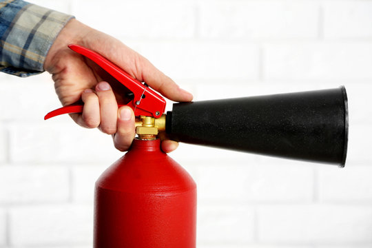 Man holding the fire extinguisher on white brick wall background