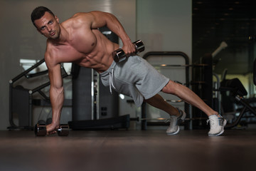 Young Man Doing Push Ups With Dumbbells On Floor