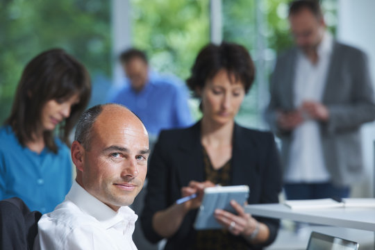 Portrait of businessman in front of colleagues in office