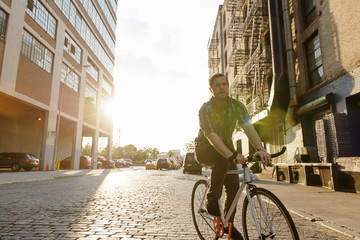 Male messenger cycling along city street