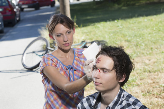 Woman cleaning man with bleeding forehead