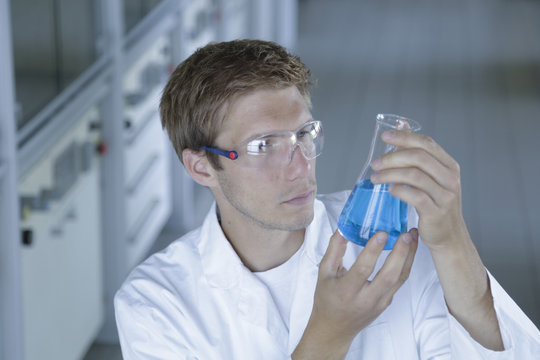 Male scientist holding up erlenmeyer flask in lab