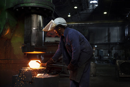 Forge worker pre forms steel billet on 5 tonne clear space hammer before it will be presented to set of two dies to be fully forged in hammer