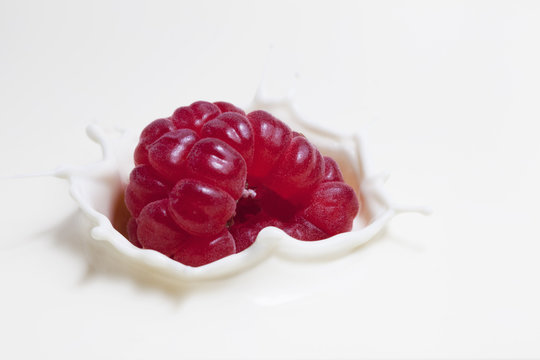 Fresh raspberry splashing onto milk surface
