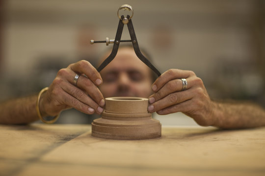 Close up of carpenter measuring turning wood in workshop