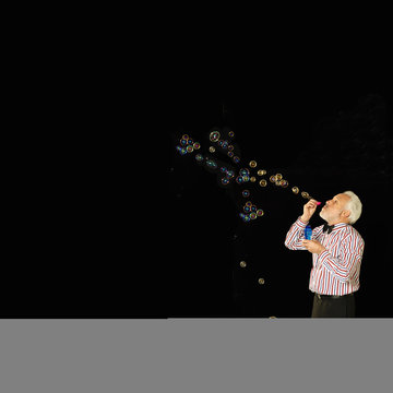 Studio shot of senior man blowing bubbles