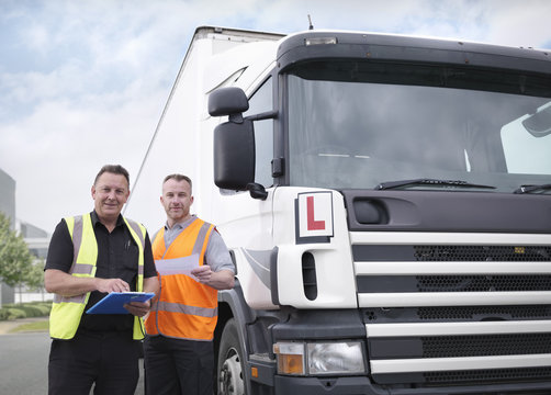 Portrait of trainee truck driver receiving pass certificate from instructor