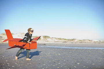Boy running with toy airplane on beach