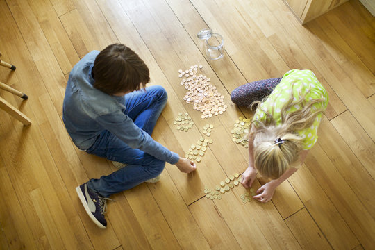 Brother and sister counting coins from savings jar