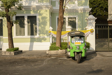 Tuk Tuk is parking in front of Wat Phra Kaeo or Grand Palace, Bangkok, Thailand. This is a beautiful scene of the palace with the twilight sky.