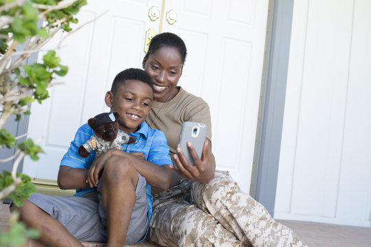 Female soldier taking selfie with son at front door on homecoming