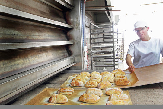 Baker putting bread onto baking sheet