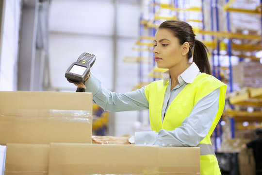 Young woman using barcode reader in distribution warehouse