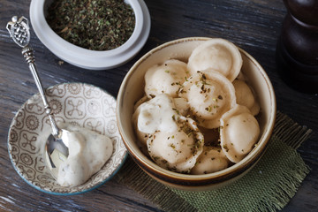 dumplings, ravioli, tortellini, pelmeni bowl, olive herb sauce, silver spoons, still life wooden