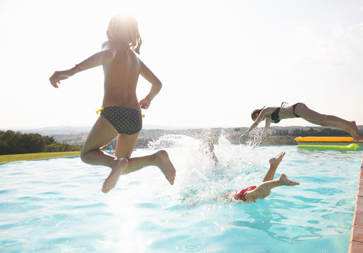 Three people jumping into swimming pool